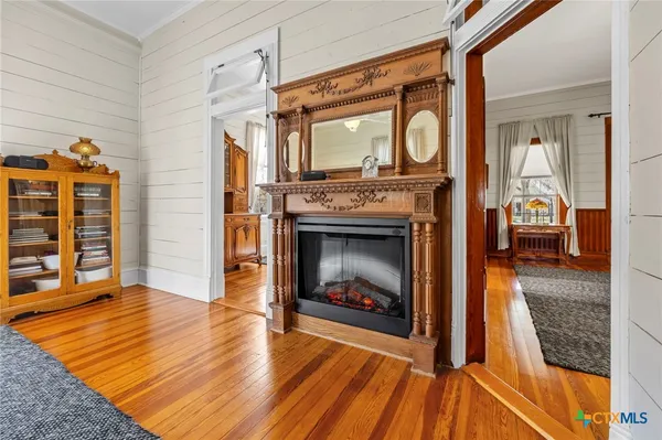 a kitchen with stainless steel appliances granite countertop a stove top oven a sink a refrigerator and white cabinets with wooden floor