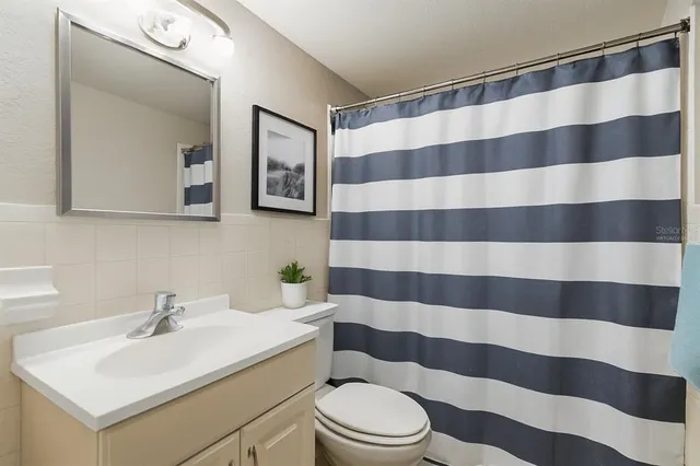 a bathroom with a sink a toilet a mirror and shower curtain
