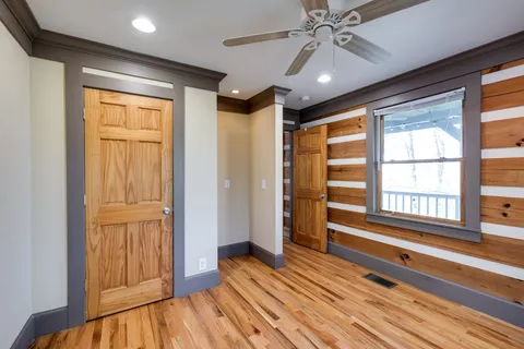 a view of empty room with wooden floor and fan