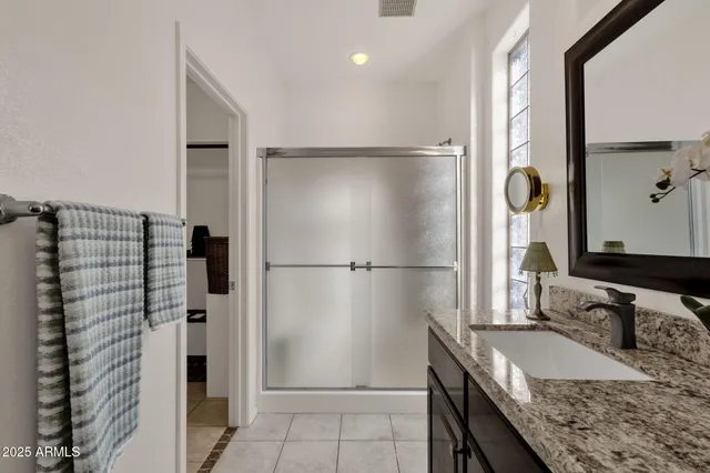 a bathroom with a granite countertop shower and mirror