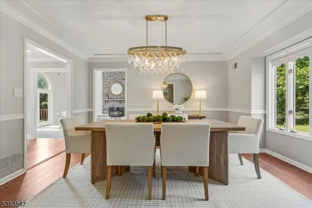 a dining room with wooden floor a chandelier a wooden table and chairs