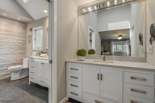 a spacious bathroom with a double vanity sink a toilet and a mirror