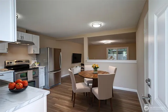 a living room with furniture a flat screen tv and kitchen view