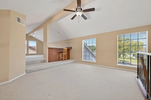 an empty room with windows and ceiling fan