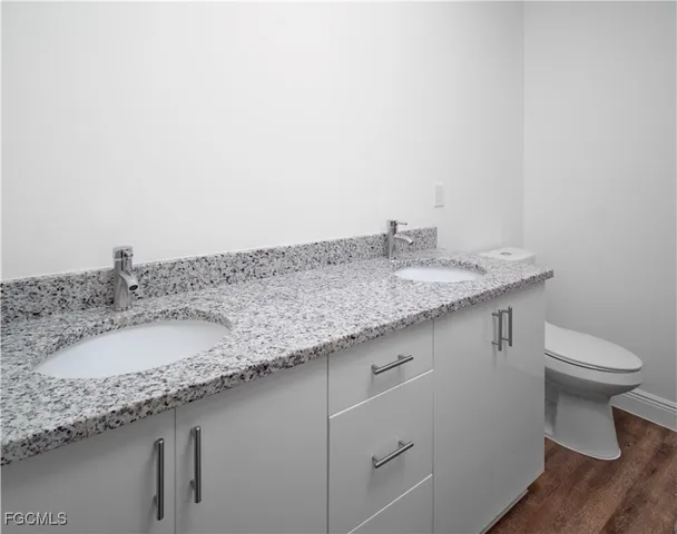 a bathroom with a granite countertop sink and a toilet