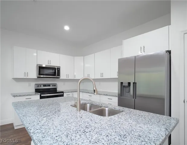 a kitchen with granite countertop a refrigerator and a sink