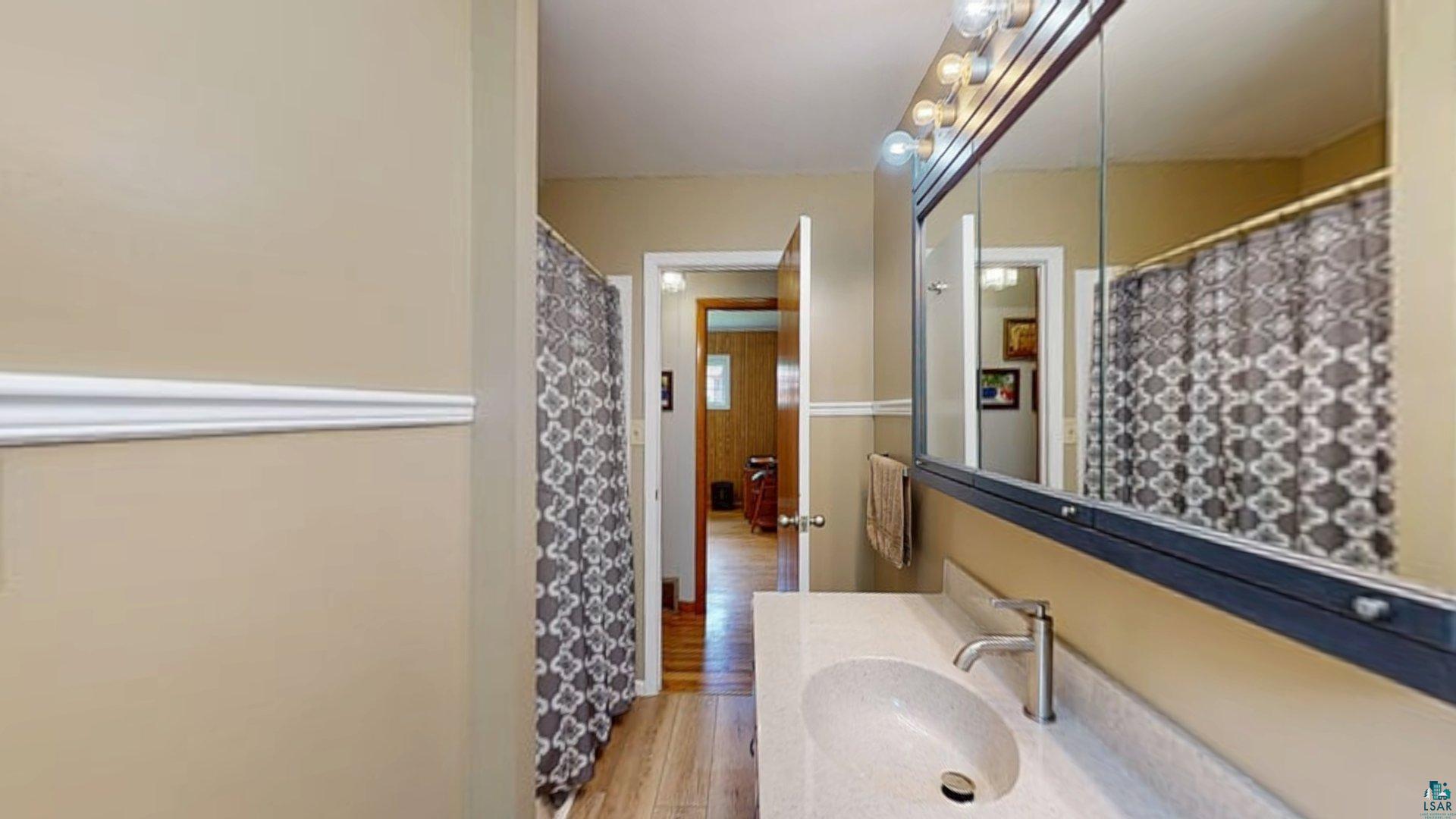 10614 Moose Lake Road Orr, MN 55771 - Photo 22 of 44 Bathroom vanity featuring an integrated sink, single-handle faucet, and mirrored medicine cabinet with overhead lighting