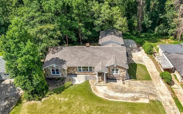 an aerial view of a house with swimming pool and large trees