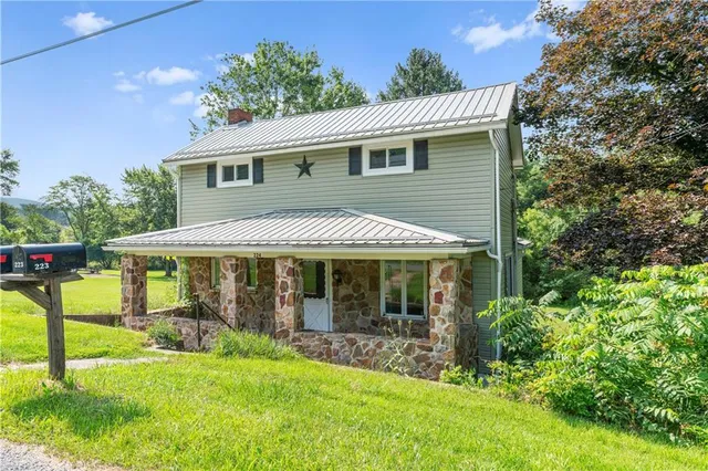 a view of a house with a yard potted plants and a large tree