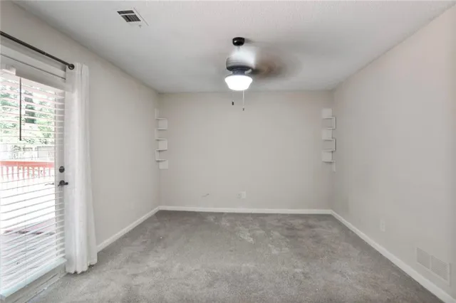 an empty room with a window and ceiling fan