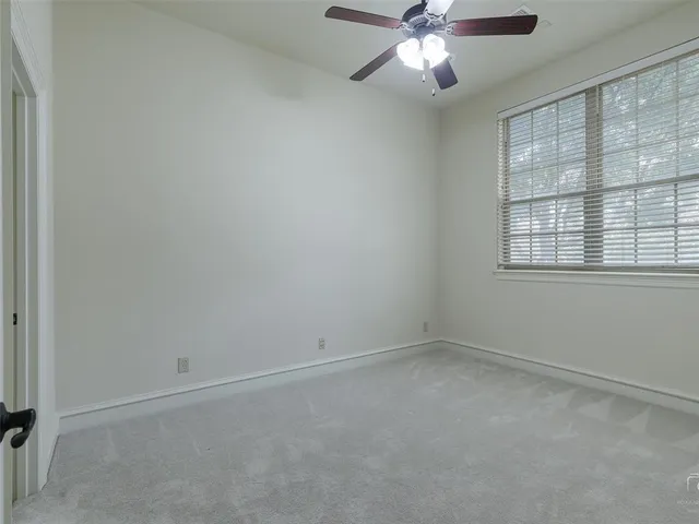 an empty room with a window and a fan