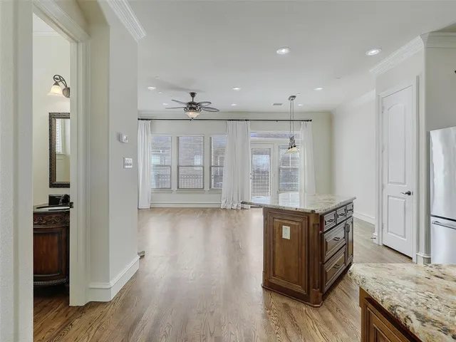 a view of an empty room with wooden floor and a kitchen