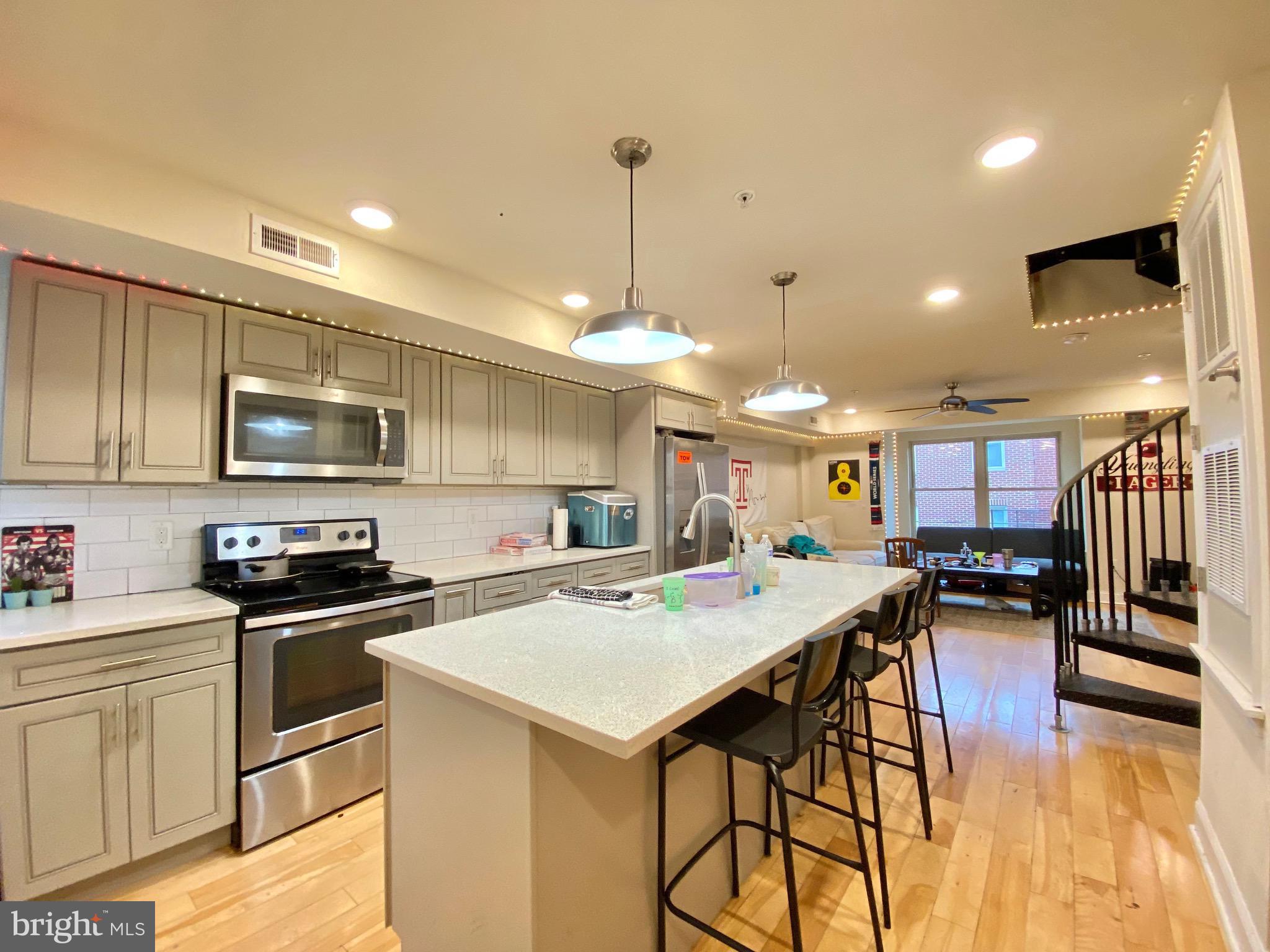 a kitchen with a stove a sink a kitchen island with chairs and wooden floor
