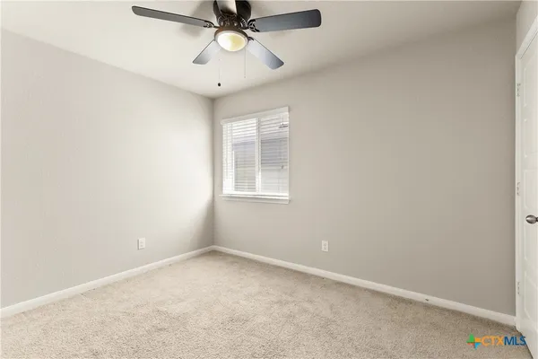 an empty room with a window and a fan
