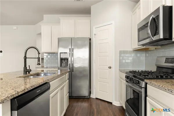 a kitchen with stainless steel appliances granite countertop a sink stove and refrigerator