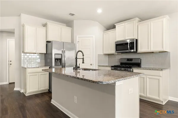 a kitchen with stainless steel appliances granite countertop a sink a stove a refrigerator a microwave and cabinets