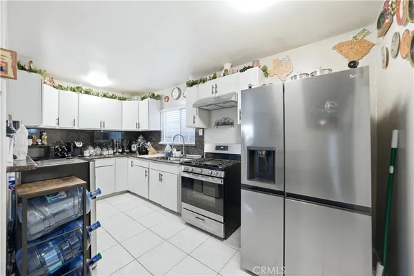 a kitchen with stainless steel appliances granite countertop a refrigerator a stove and a sink