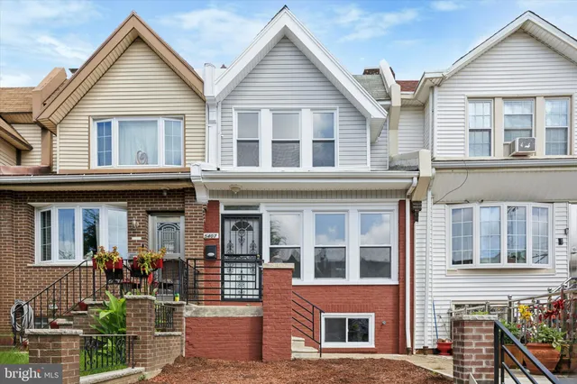 a view of a brick house with large windows and plants