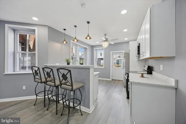 a kitchen with stainless steel appliances granite countertop a dining table chairs stove refrigerator and cabinets