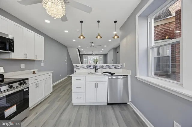 a kitchen with stainless steel appliances a white stove top oven a sink dishwasher and a refrigerator with wooden floor