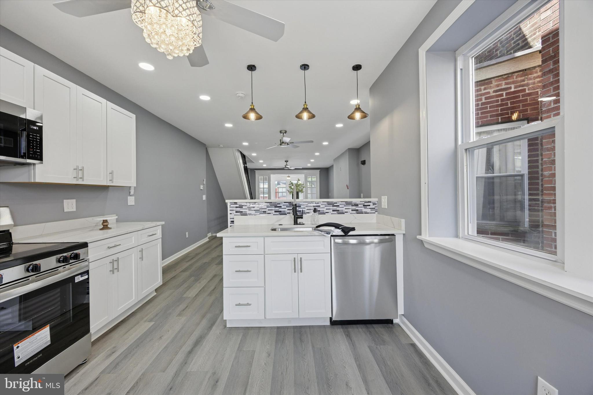 5407 Arlington Street Philadelphia, PA 19131 - Photo 8 of 15 a kitchen with stainless steel appliances a white stove top oven a sink dishwasher and a refrigerator with wooden floor