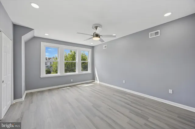 a view of an empty room with a window and wooden floor