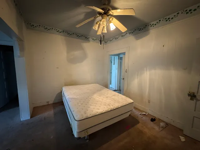 an empty room with a chandelier fan and closet