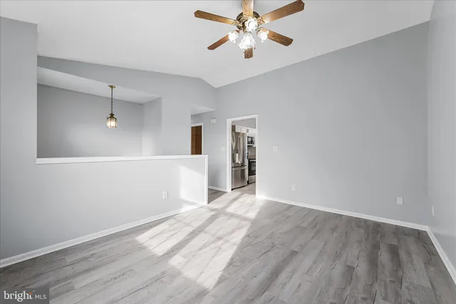 a view of an empty room with window and wooden floor