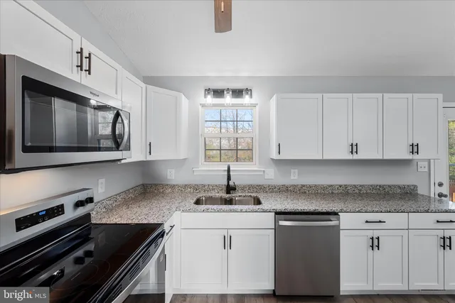 a kitchen with granite countertop a sink stove and microwave