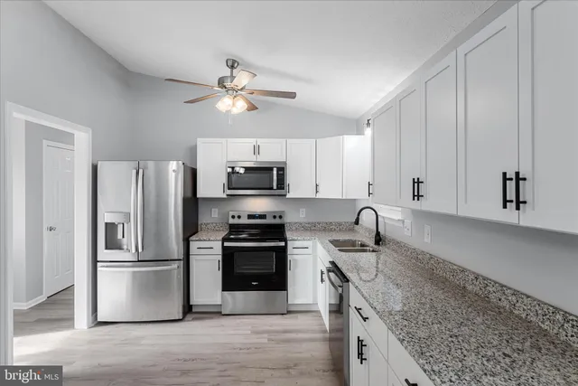 a kitchen with stainless steel appliances granite countertop a refrigerator stove a sink and dishwasher with wooden floor