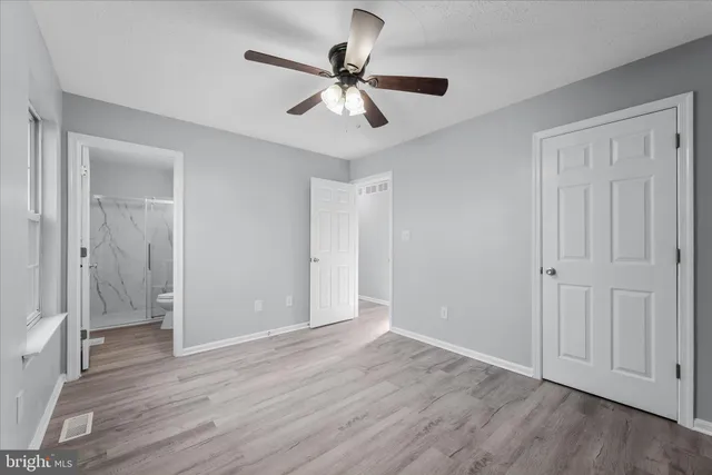 a view of empty room with wooden floor and ceiling fan