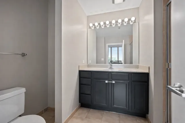 a bathroom with a granite countertop sink a toilet and a mirror