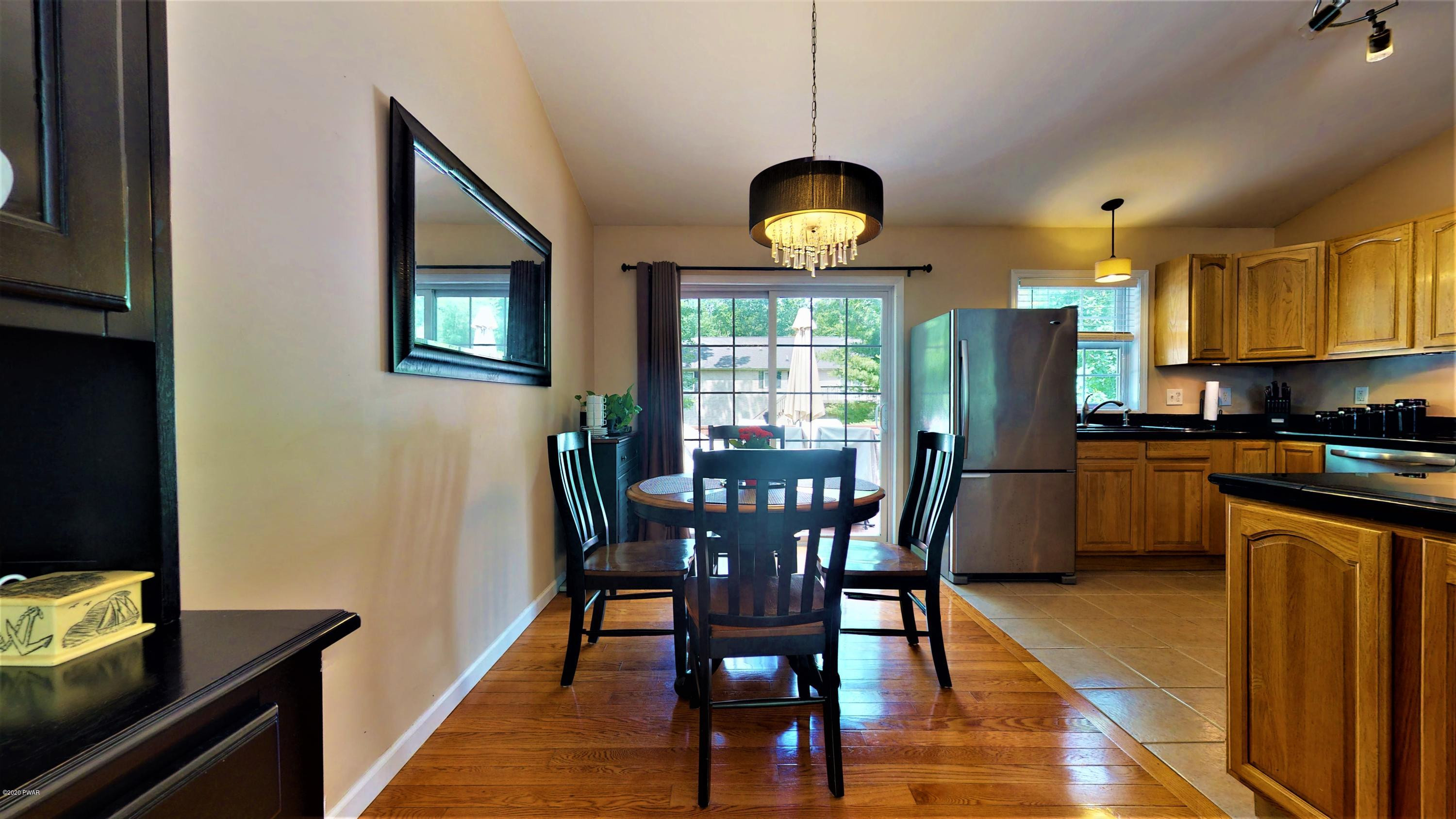 143 Raccoon Road Dingmans Ferry, PA 18328 - Photo 39 of 87 a kitchen with stainless steel appliances granite countertop a stove a refrigerator a kitchen island a dining table and chairs with wooden floor