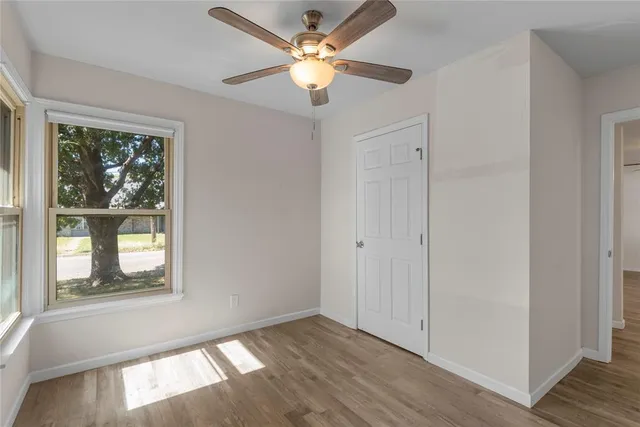 a view of an empty room with a window and wooden floor
