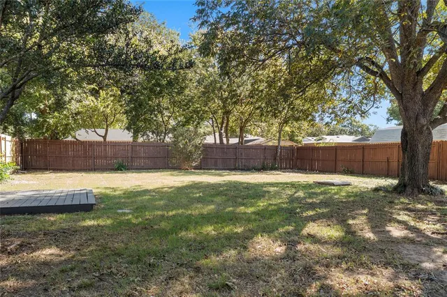a view of a yard with a large tree and wooden fence