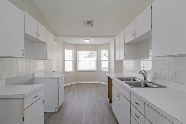 a kitchen with white cabinets and wooden floors