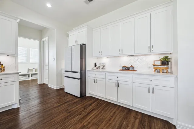 a kitchen with stainless steel appliances granite countertop a refrigerator sink and white cabinets