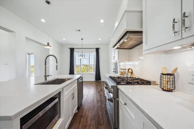 a kitchen with kitchen island stainless steel appliances a sink stove and cabinets