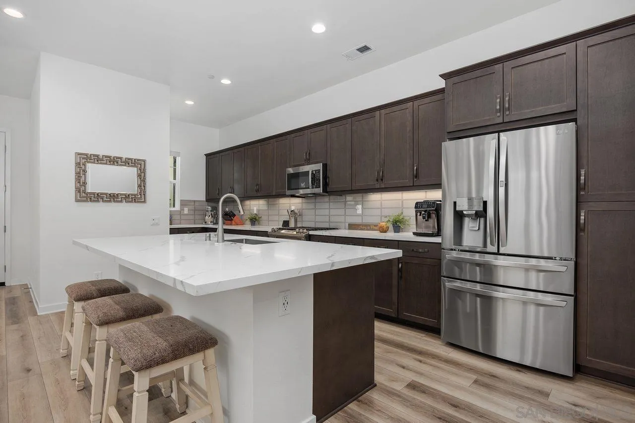 565 Townsend Way San Marcos, CA 92078 - Photo 7 of 33 a kitchen with stainless steel appliances a refrigerator a stove a sink and a refrigerator with wooden floor