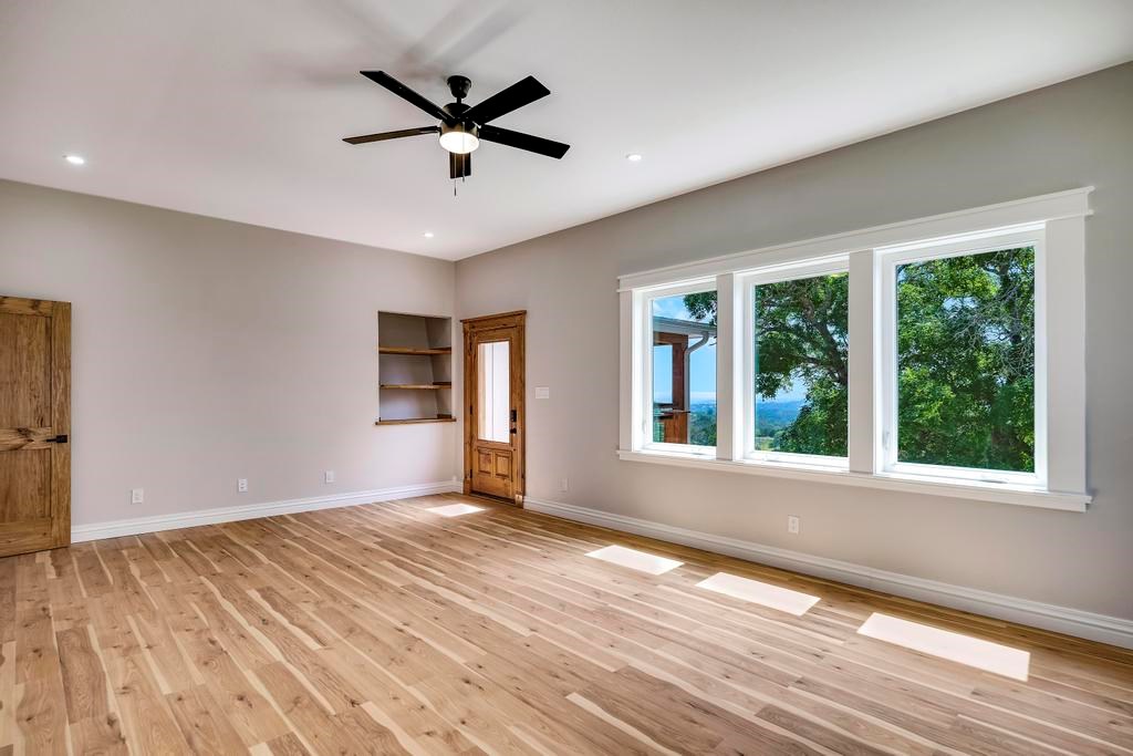 111 Stoney Hills Road Center Point, TX 78010 - Photo 42 of 61 an empty room with wooden floor fan and windows