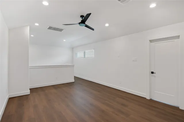 an empty room with wooden floor fan and windows