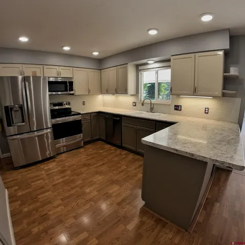 a kitchen with stainless steel appliances granite countertop a refrigerator a sink a stove a microwave and island