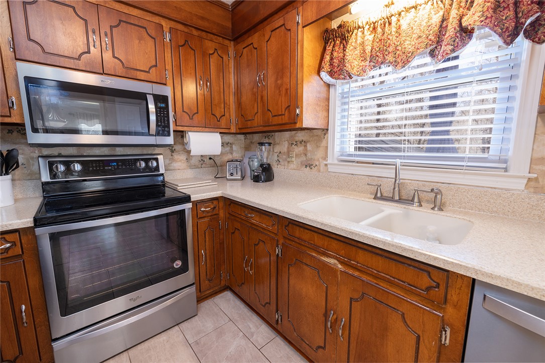 404 South Old Mill Road Seneca, SC 29678 - Photo 12 of 39 Rich wood cabinetry surrounds integrated stainless steel appliances and a double-bowl sink near the window.