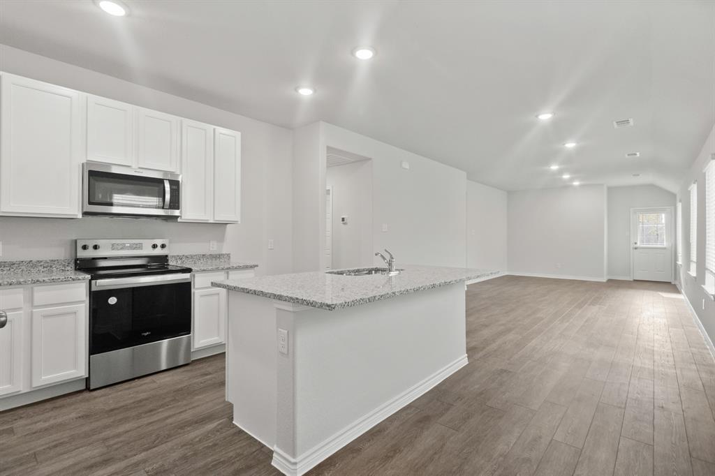 1609 Romans Road Ennis, TX 75119 - Photo 6 of 17 a kitchen with stainless steel appliances kitchen island granite countertop a stove a sink and a microwave