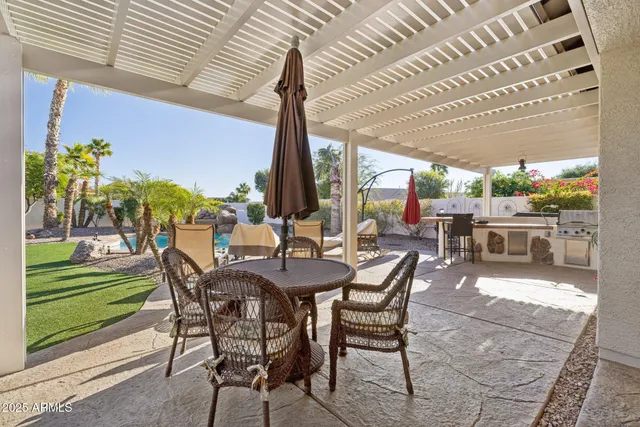 a view of a patio with table and chairs potted plants and floor to ceiling window