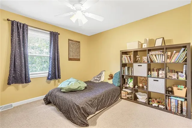a bedroom with a bed bookshelf and a large window