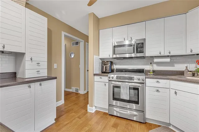 a kitchen with stainless steel appliances granite countertop a stove a sink and white cabinets