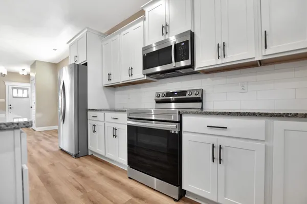 a kitchen with stainless steel appliances granite countertop a refrigerator stove and white cabinets