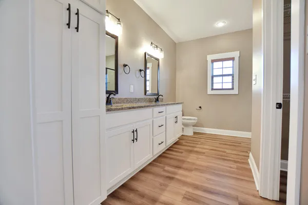 a bathroom with a granite countertop sink mirror and a toilet