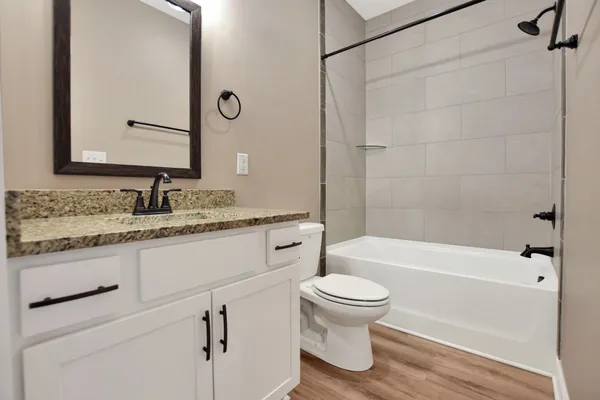 a bathroom with a granite countertop toilet sink and mirror with bathtub